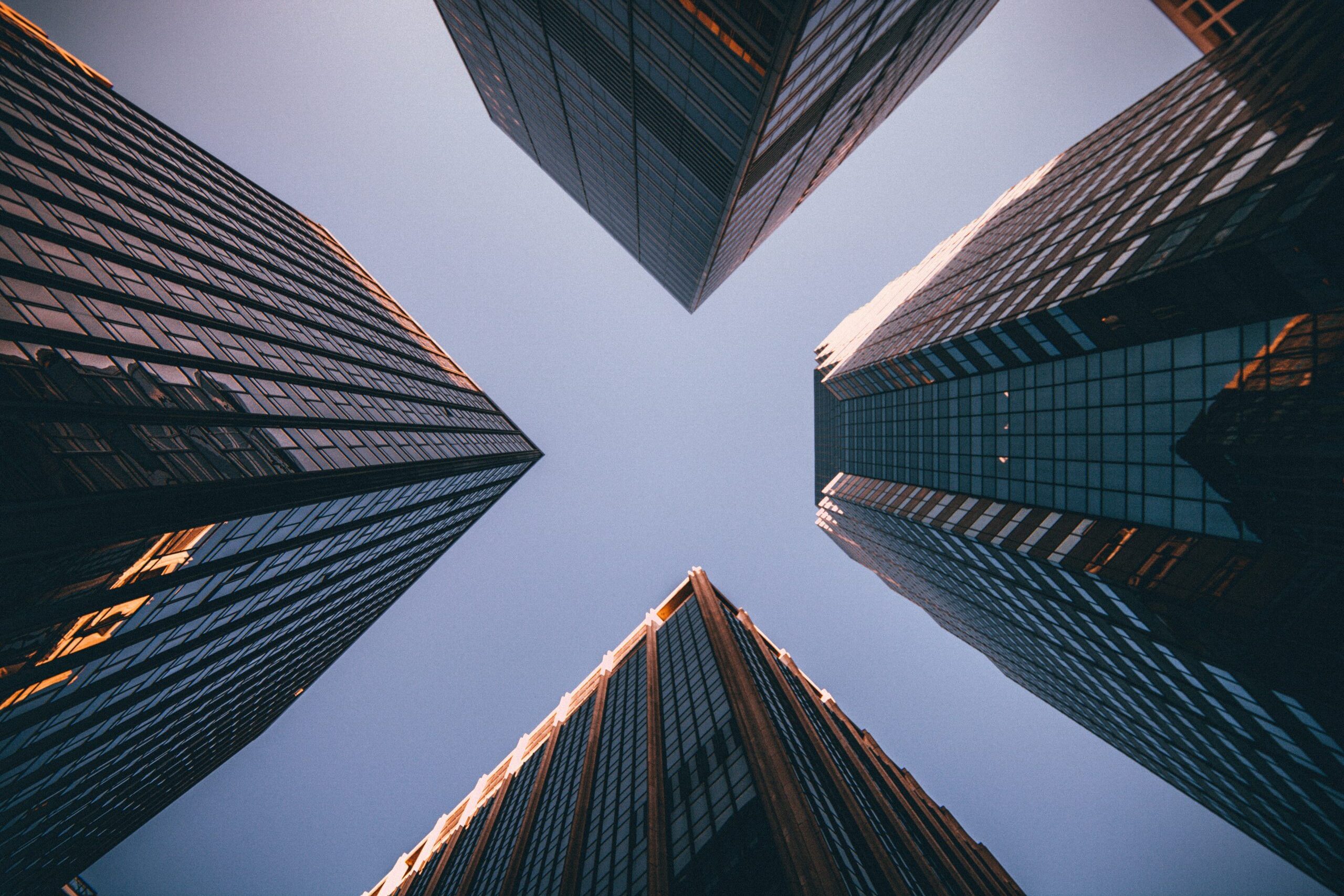 Imagem apresentando prédios corporativos grandes e imponantes vistos de baixo para cima.